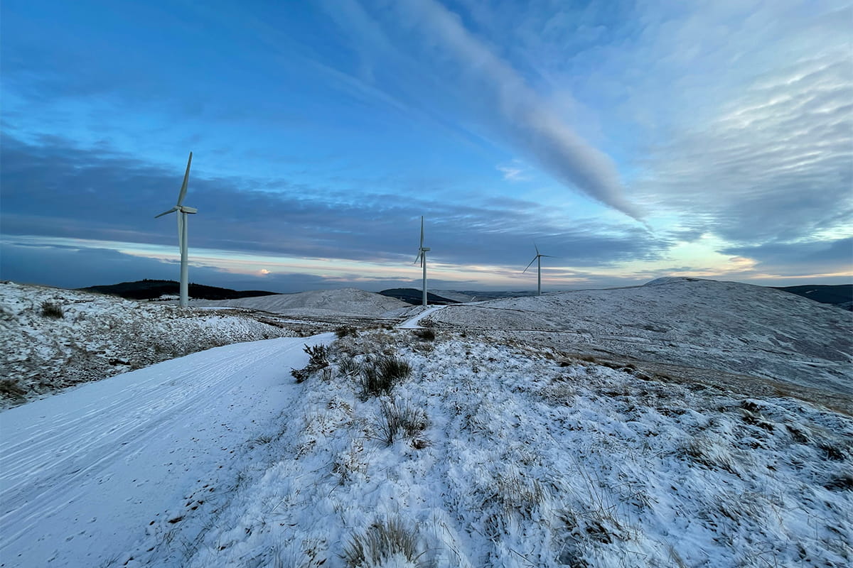 Line of three wind turbines on a hill in winter