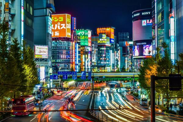 A busy street in Tokyo at night time with lots of colourful lights and advertising