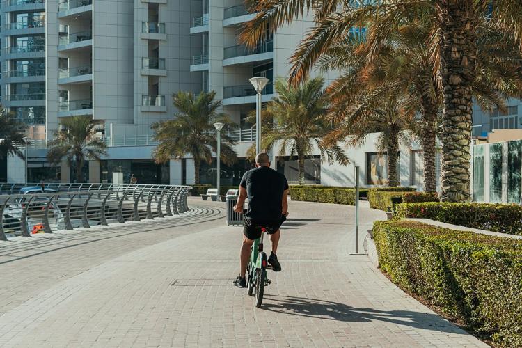 Man cycling on pedestrian and cycling path in front of apartment buildings