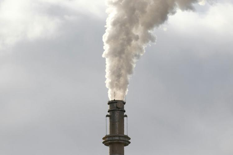 Smoke coming out of an industrial chimney against a cloudy sky