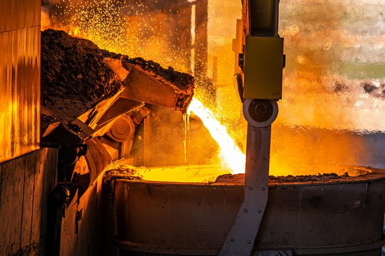 Close up molten metal pouring into a container in a steel factory