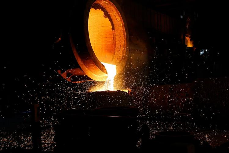 Close-up of molten steel flowing out of a container in a steel production plant
